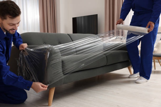 Movers carefully wrapping furniture with protective film and pads