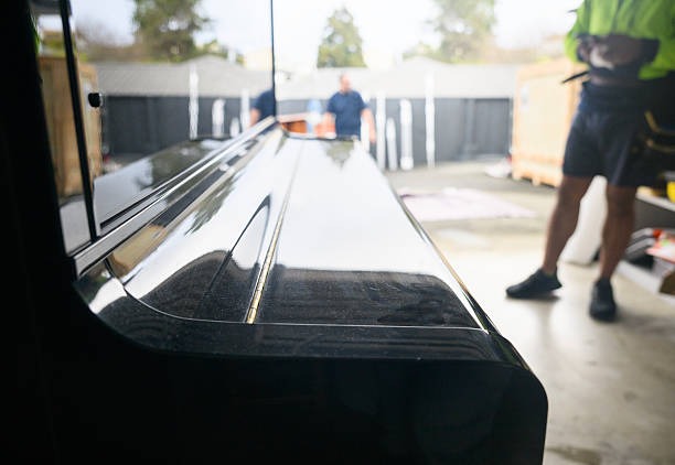 Movers carefully maneuvering piano through doorways